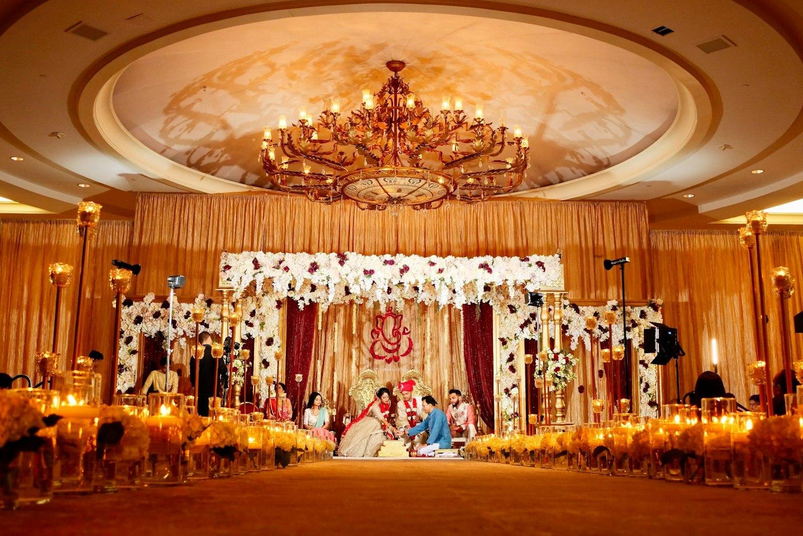Wedding mandap under a crystal chandelier in a decorated ballroom